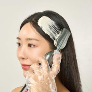 Henna being brushed onto a woman's hair